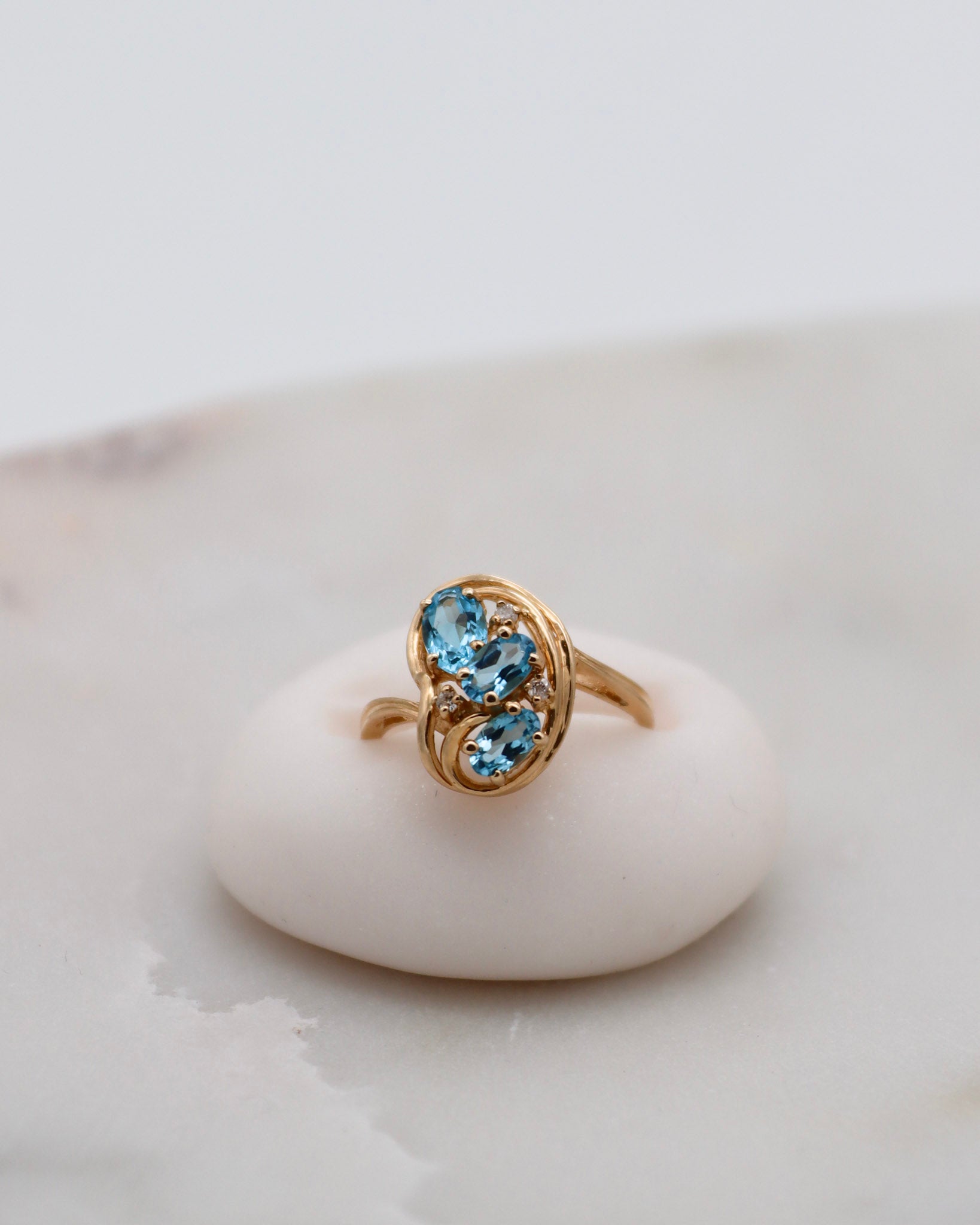 Vintage-Ring Theresa mit 0.60ct blauen Topasen & 0.05ct Brillanten, geschwungene Ringschiene aus 585/-Gelbgold – erhältlich in München und Augsburg