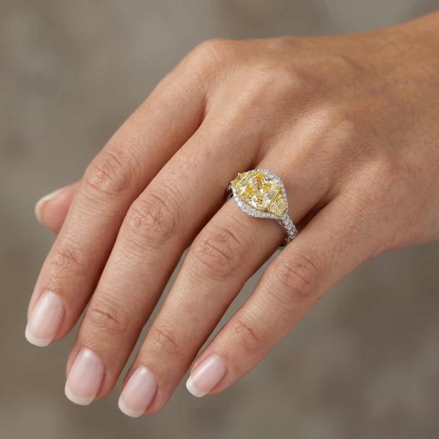 Gelber Kissenschliff-Diamantring mit drei Steinen und Halo-Fassung