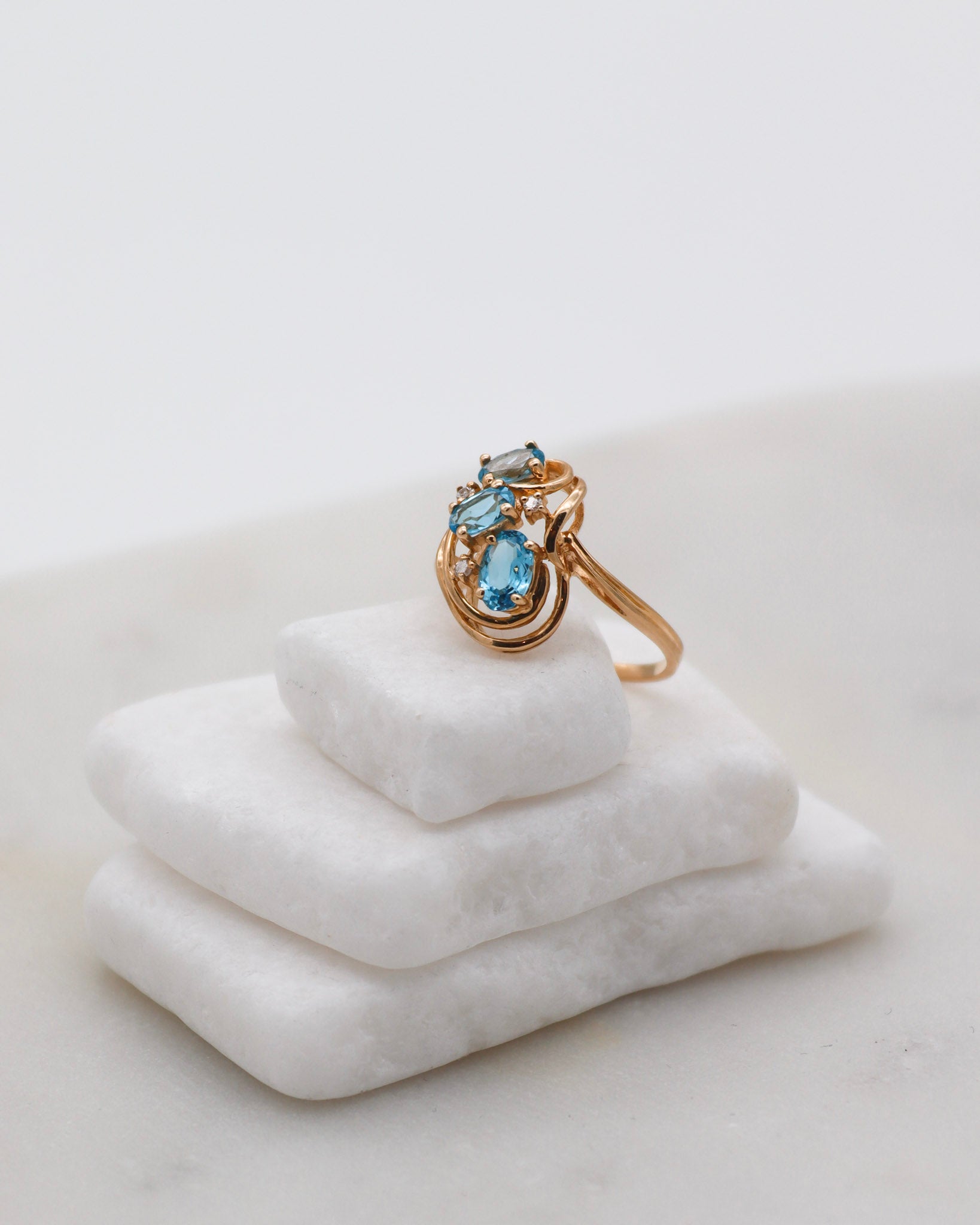 Vintage-Ring Theresa mit 0.60ct blauen Topasen & 0.05ct Brillanten, geschwungene Ringschiene aus 585/-Gelbgold – erhältlich in München und Augsburg